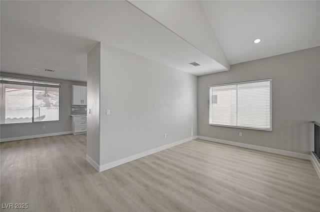 empty room featuring light wood-style floors, visible vents, and baseboards