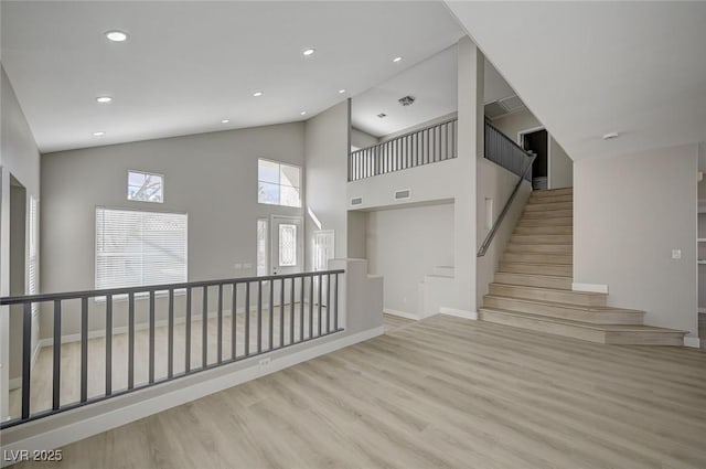 empty room with visible vents, stairway, wood finished floors, high vaulted ceiling, and recessed lighting