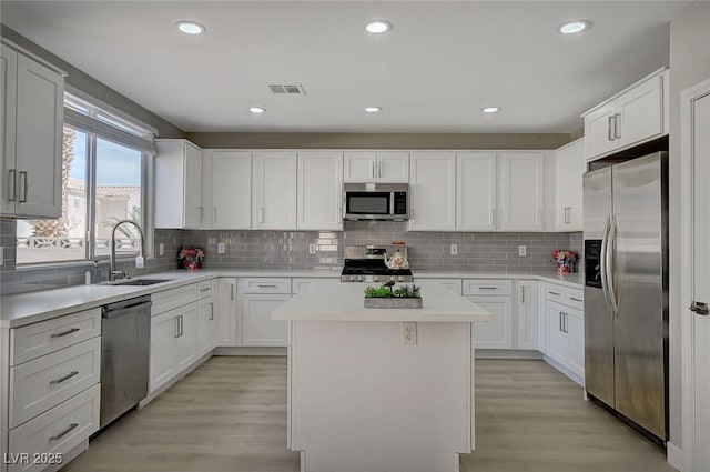 kitchen with a kitchen island, a sink, visible vents, light wood-style floors, and appliances with stainless steel finishes