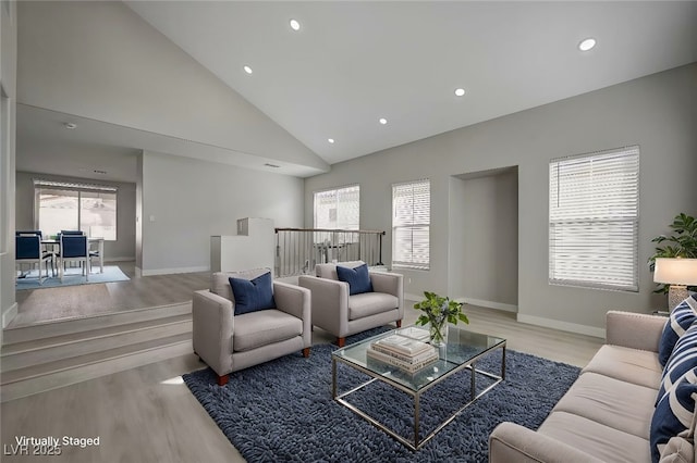 living area featuring high vaulted ceiling, a wealth of natural light, and wood finished floors