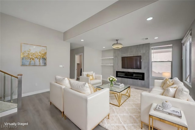 living room featuring visible vents, a large fireplace, wood finished floors, baseboards, and stairs