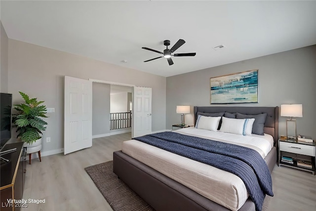 bedroom featuring light wood finished floors, baseboards, visible vents, and a ceiling fan