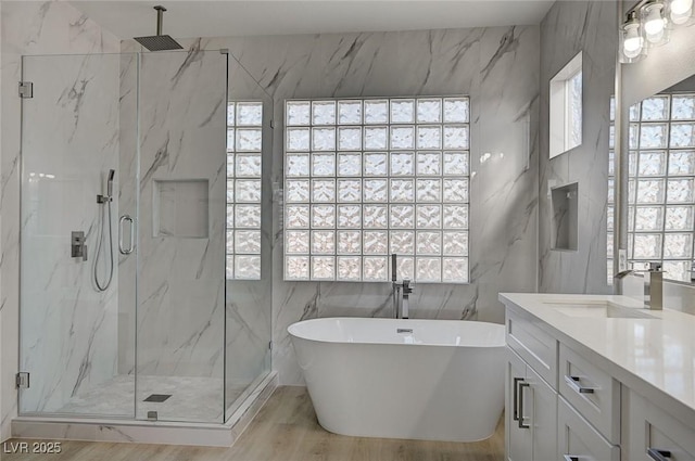 full bath with tile walls, a marble finish shower, a soaking tub, vanity, and wood finished floors