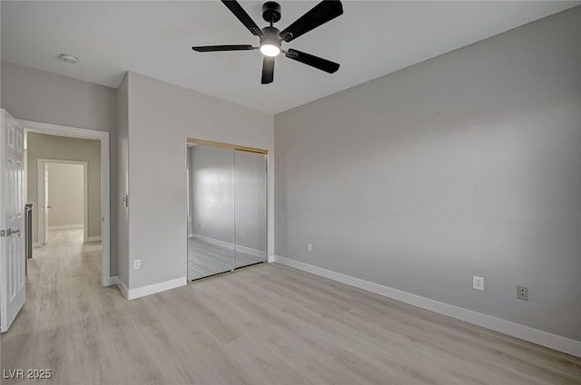 unfurnished bedroom featuring a ceiling fan, a closet, light wood-style flooring, and baseboards