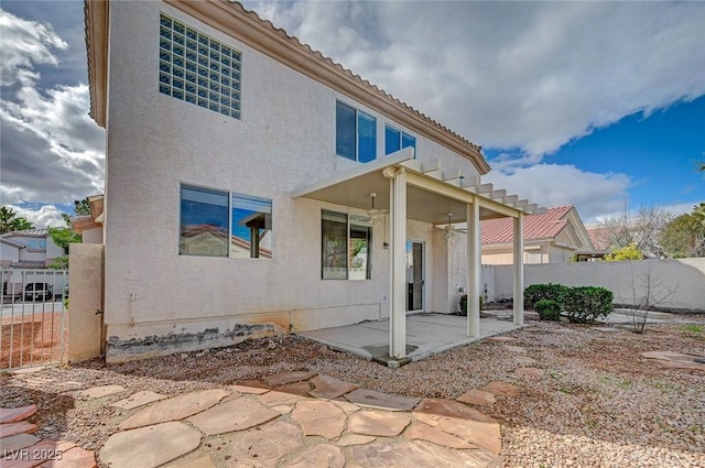 rear view of property with a patio area, fence, a tile roof, and stucco siding