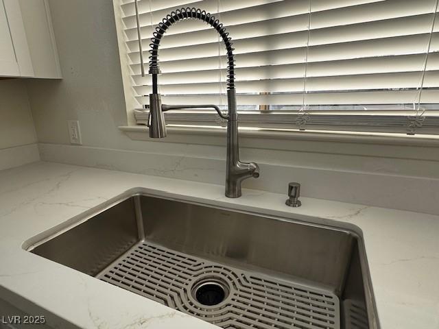 interior details with light stone counters, white cabinets, and a sink