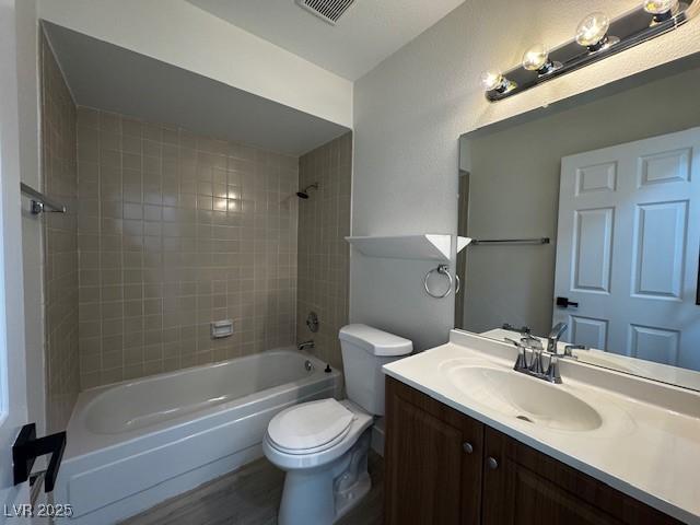 full bathroom featuring bathing tub / shower combination, visible vents, toilet, vanity, and wood finished floors