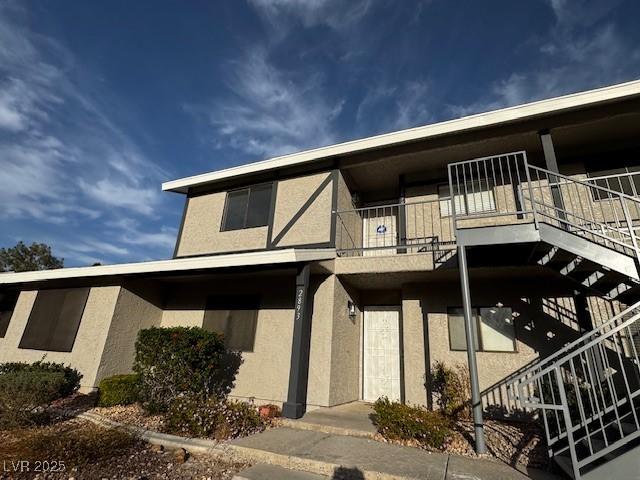 exterior space featuring a balcony, stairs, and stucco siding