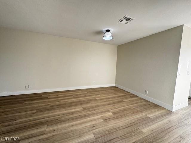 empty room featuring visible vents, baseboards, and wood finished floors