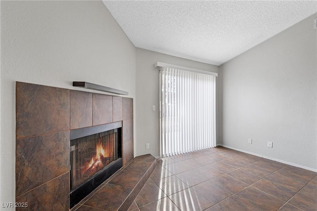 unfurnished living room with a tile fireplace, a textured ceiling, and dark tile patterned floors