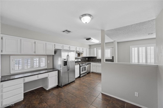 kitchen featuring stainless steel appliances, dark countertops, visible vents, and under cabinet range hood