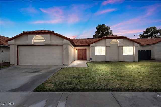 mediterranean / spanish home with stucco siding, concrete driveway, a front yard, a garage, and a tiled roof