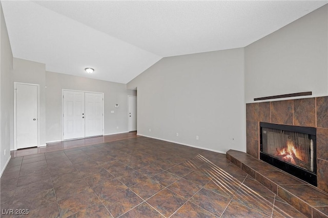 unfurnished living room featuring a tile fireplace, lofted ceiling, and baseboards