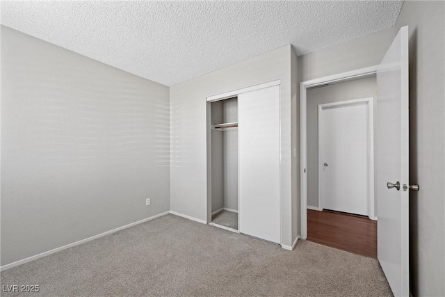 unfurnished bedroom featuring a textured ceiling, carpet floors, a closet, and baseboards