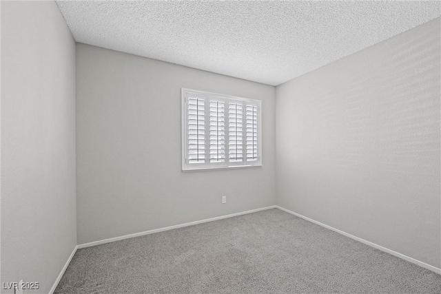 spare room featuring carpet floors, a textured ceiling, and baseboards