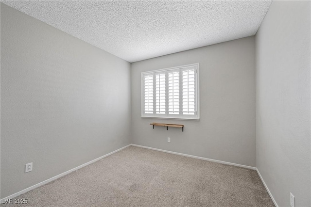 spare room with carpet flooring, a textured ceiling, and baseboards