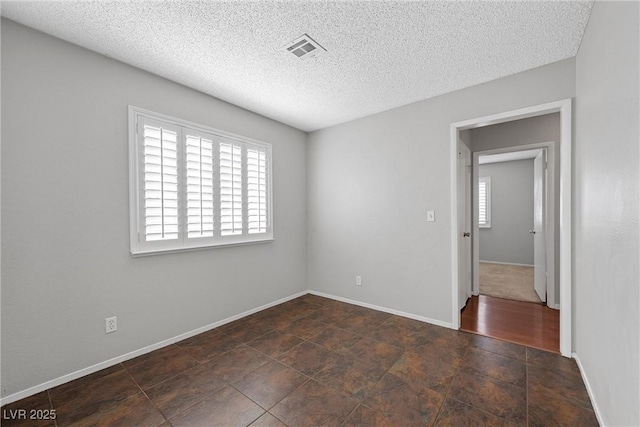 unfurnished room with baseboards, a textured ceiling, visible vents, and a healthy amount of sunlight