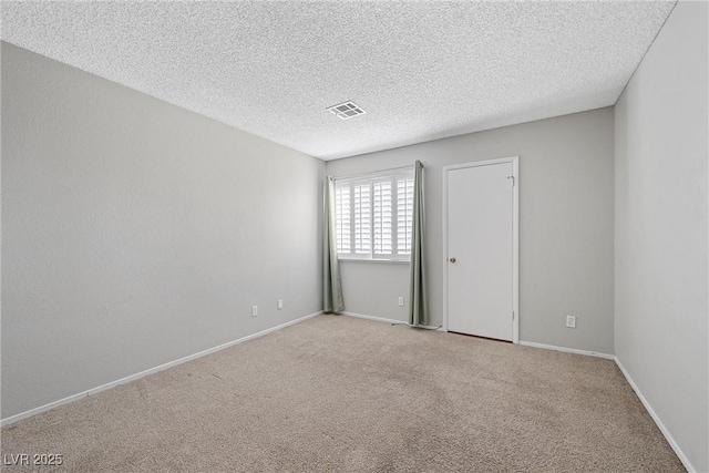 carpeted empty room with visible vents, a textured ceiling, and baseboards