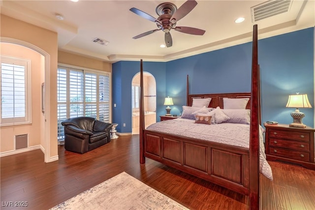 bedroom featuring arched walkways, dark wood-style flooring, visible vents, and baseboards