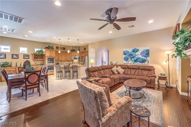 living area featuring arched walkways, visible vents, and wood finished floors