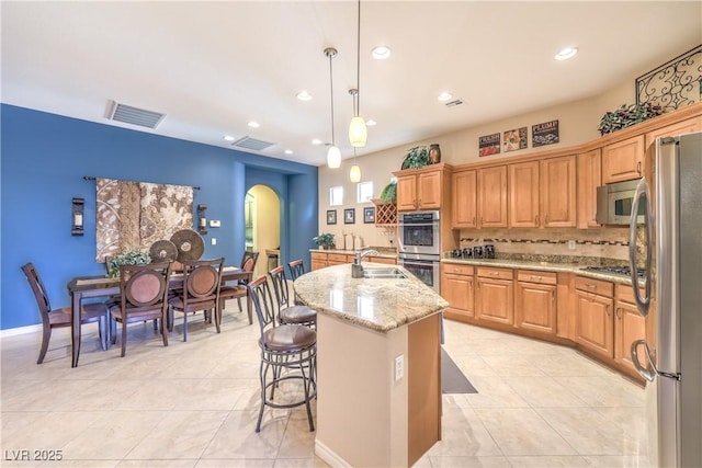 kitchen featuring arched walkways, stainless steel appliances, a sink, and visible vents