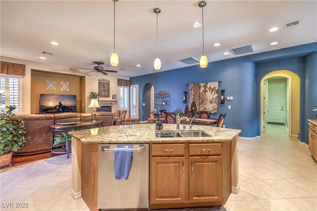 kitchen featuring arched walkways, visible vents, open floor plan, stainless steel dishwasher, and an island with sink