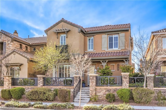 mediterranean / spanish-style home with stone siding, a porch, a tile roof, and stucco siding