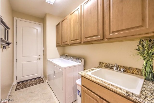 laundry area featuring light tile patterned flooring, a sink, baseboards, cabinet space, and washer and clothes dryer