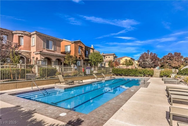 community pool featuring a residential view, a patio area, and fence