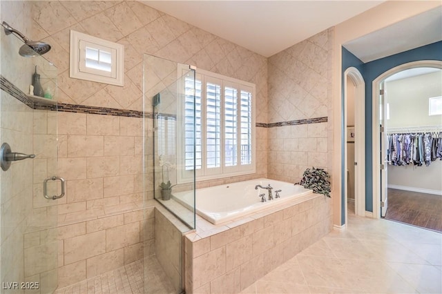 full bathroom with a garden tub, a spacious closet, a stall shower, baseboards, and tile patterned floors