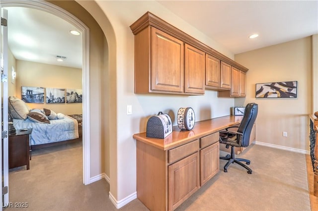 office area with arched walkways, recessed lighting, light colored carpet, baseboards, and built in study area