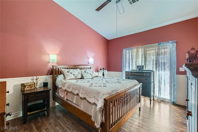 bedroom with visible vents, wainscoting, lofted ceiling, ceiling fan, and wood finished floors