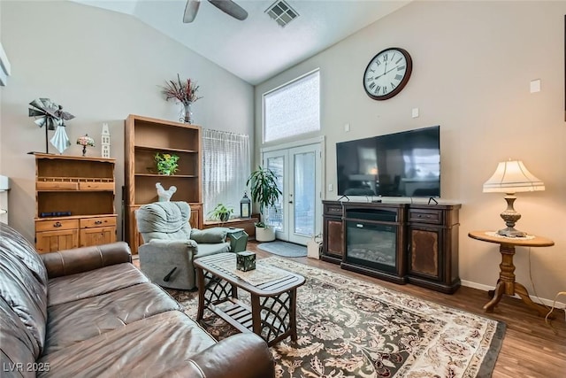 living room featuring visible vents, ceiling fan, wood finished floors, high vaulted ceiling, and baseboards