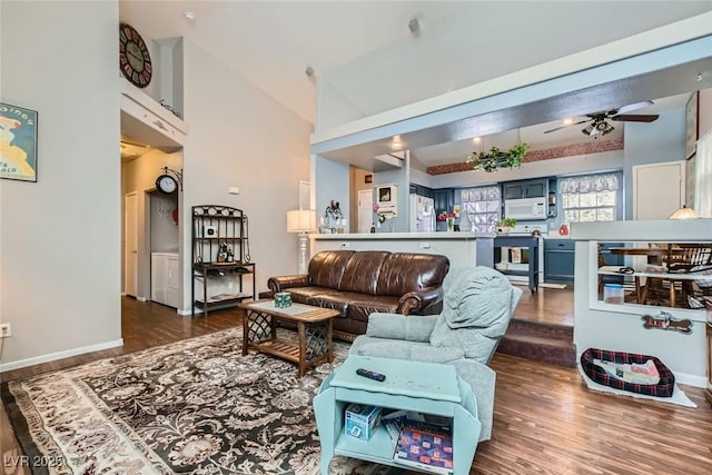 living area featuring high vaulted ceiling, wood finished floors, a ceiling fan, and baseboards