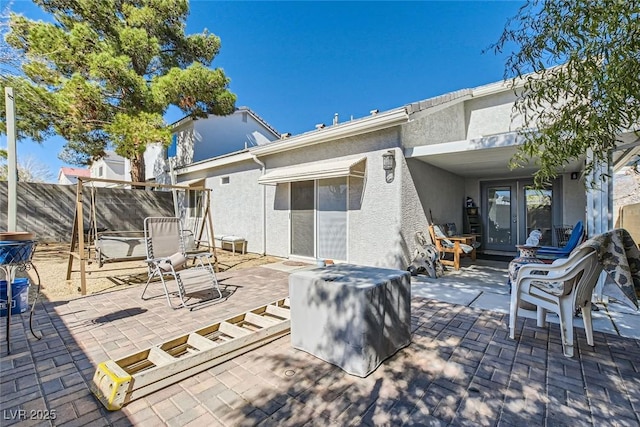 rear view of house featuring fence, a patio, and stucco siding