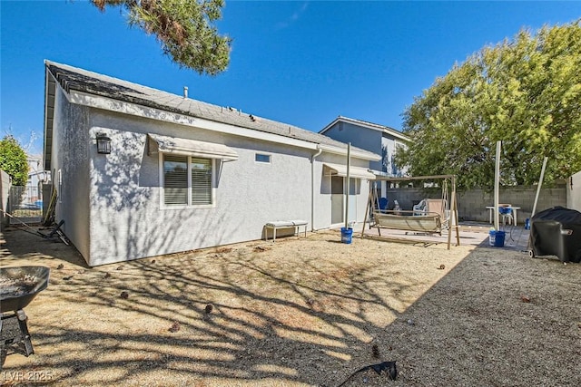 rear view of property with a patio area, fence, and stucco siding