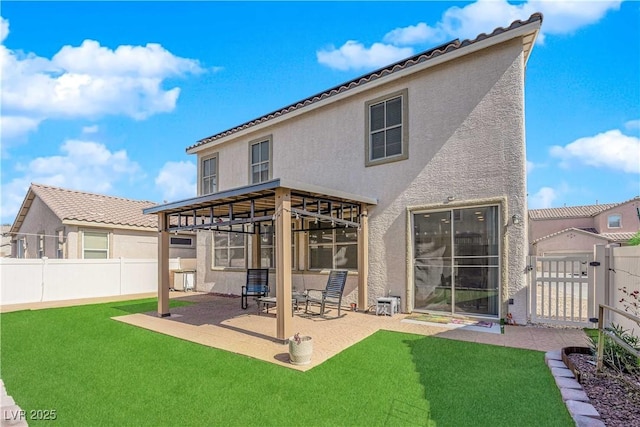 back of house featuring a yard, a patio area, a gate, and stucco siding