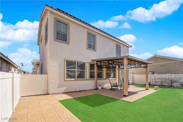 rear view of house featuring a patio, a fenced backyard, a yard, a gazebo, and stucco siding