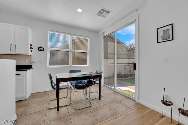 dining space with light tile patterned floors, visible vents, and baseboards