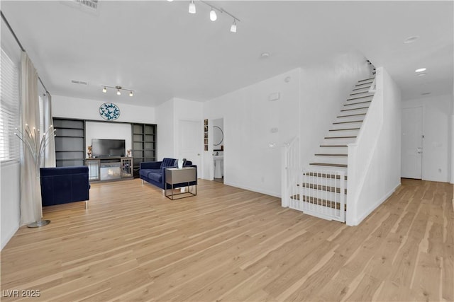 living area with stairs, visible vents, track lighting, and wood finished floors