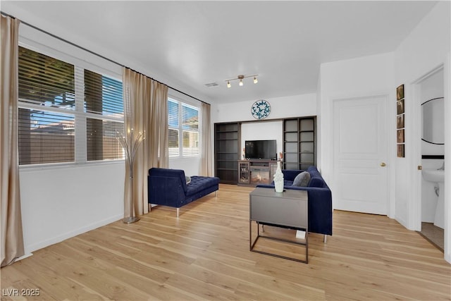 living room with baseboards, visible vents, and light wood finished floors