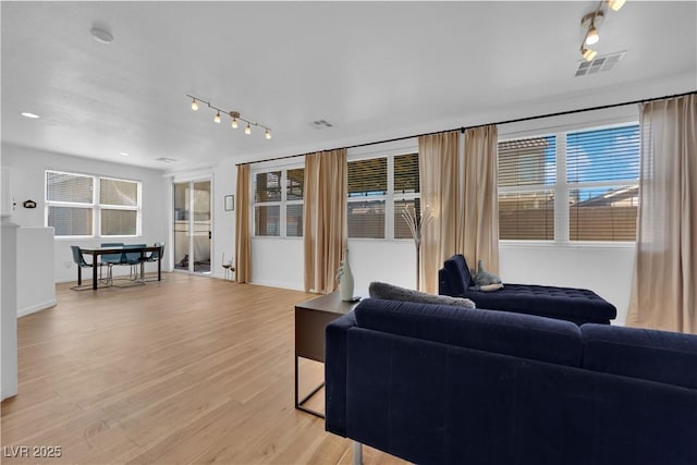 living area with light wood finished floors, rail lighting, visible vents, and a healthy amount of sunlight