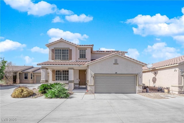 mediterranean / spanish-style house with concrete driveway, a tile roof, an attached garage, and stucco siding