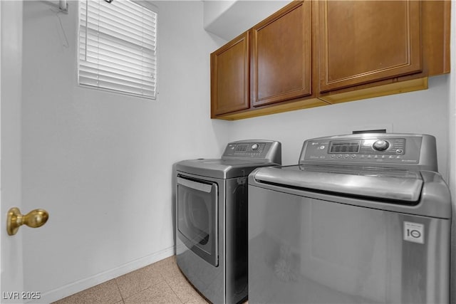 laundry room featuring washing machine and dryer, cabinet space, and baseboards