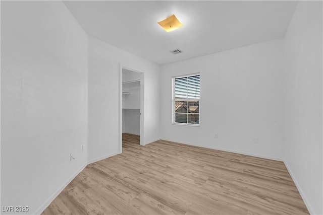 unfurnished room with light wood-type flooring, visible vents, and baseboards