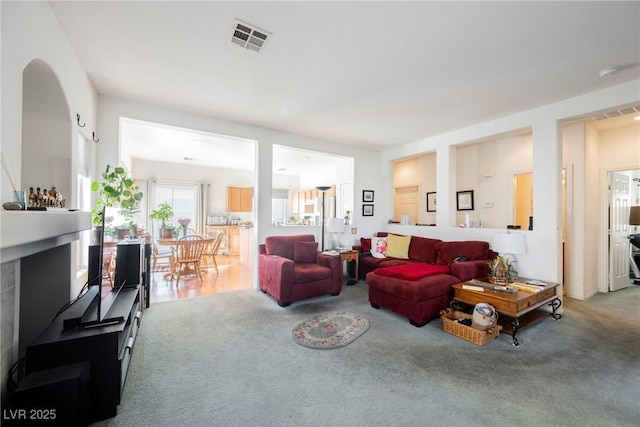 carpeted living area with a fireplace and visible vents