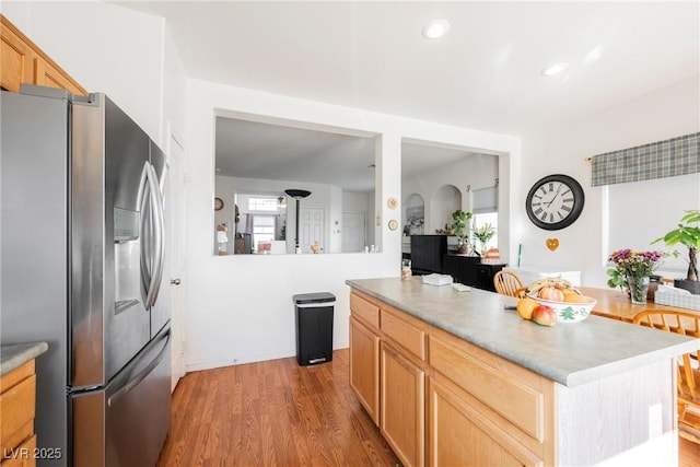 kitchen with a center island, stainless steel refrigerator with ice dispenser, light countertops, light brown cabinets, and wood finished floors