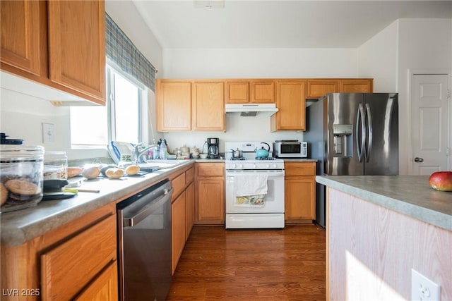 kitchen with dark wood-style floors, stainless steel appliances, light countertops, under cabinet range hood, and a sink