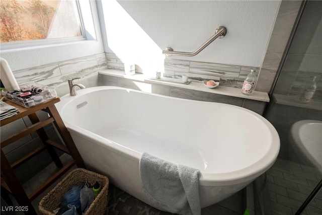 full bath with tile walls and a freestanding bath