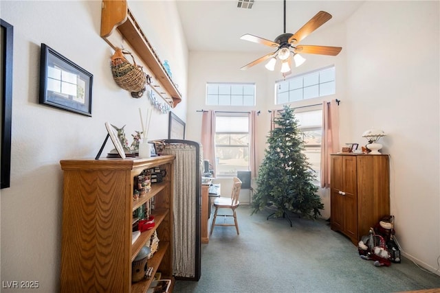 living area with visible vents, a high ceiling, carpet, and a ceiling fan